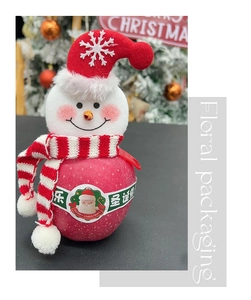 Dettaglio di una mela natalizia decorata con testa di pupazzo di neve in peluche e sciarpa