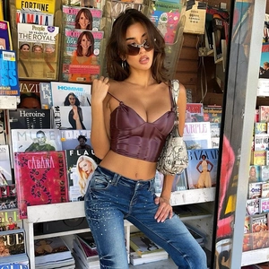 Deep purple faux leather crop top paired with embellished jeans in a street style setting