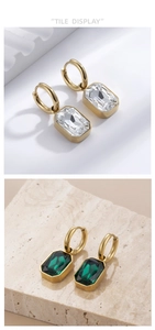 Detail of square-cut zircon drop earrings in white and emerald green with gold plating