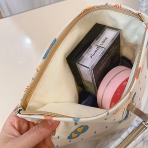 Detail of printed canvas cosmetic bag showing inner capacity for makeup storage