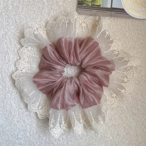 Macro shot of large pink satin scrunchie featuring elegant white lace embroidery detail