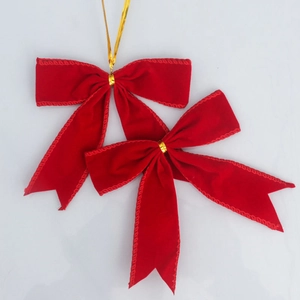 Détails de nœuds de Noël en velours rouge avec attaches dorées sur fond blanc uni