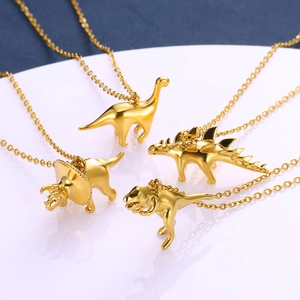 Detailed set of four dinosaur pendant necklaces in polished gold finish on display tray