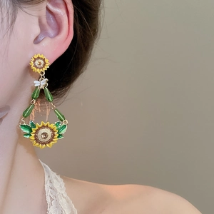 Macro shot of vibrant sunflower and green bead earrings on model in soft lighting