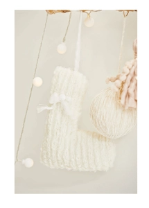 Detail of white knit Christmas letter L ornament with bow and warm string lights