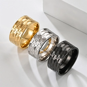 Macro detail of wide hammered texture rings in gold, silver, and black titanium steel