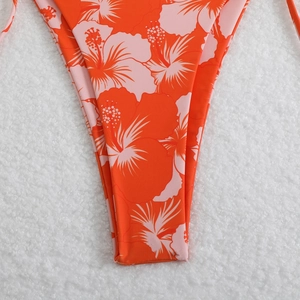 Close-up of vibrant orange bikini bottoms with pink tropical hibiscus floral print