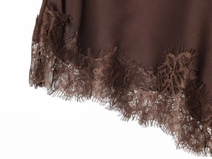 Detailed view of dark brown silky satin fabric with intricate eyelash lace trim edge