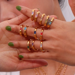 Stack of 18K gold plated rings featuring colorful rectangular zircon stones on model's hand