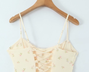 Detail view of yellow floral dress with adjustable lace-up back design on a wooden hanger