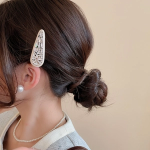 Close-up of elegant hair clip with rectangular zircons worn by model on side hair