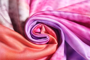 Macro shot of gradient knit fabric with pink, purple, and orange woven textures