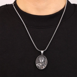 Close-up of vintage silver Jesus pendant with detailed embossing on a metal chain