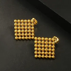 Golden 18k plated stainless steel square bead stud earrings on black texture surface