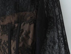 Détail macro de dentelle florale noire avec doublure beige sur un haut corset féminin