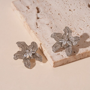 Macro shot of silver flower earrings with clear zircon stones on natural stone base