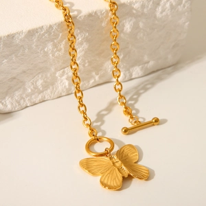 Golden butterfly pendant necklace with elegant OT clasp on a white stone surface