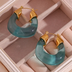 Macro detail of U-shaped gold-tone and translucent sea blue earrings in a velvet box