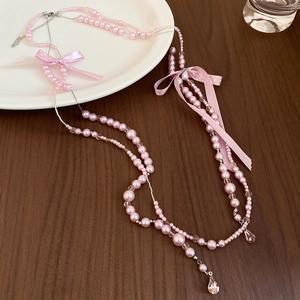 Close-up of a double-layer pink pearl necklace with ribbon bows and crystal drops