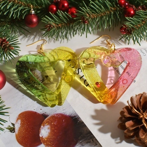 Detail of glittery heart-shaped resin earrings with festive Christmas background