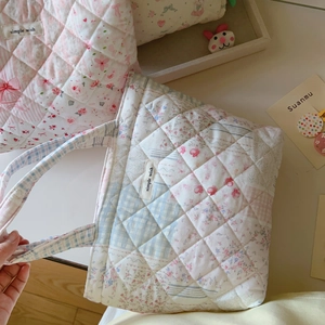 Detailed macro view of floral quilted cotton tote bag with pink patchwork and logo