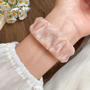 Close-up of marbled amber acrylic triangle bracelet on wrist with elegant white fabric