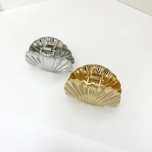 Detailed view of gold and silver seashell hair claws with metallic texture and springs