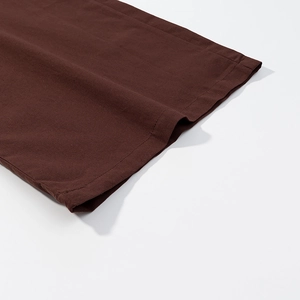 Gros plan des coutures et de l'ourlet sur un pantalon en coton de couleur marron foncé