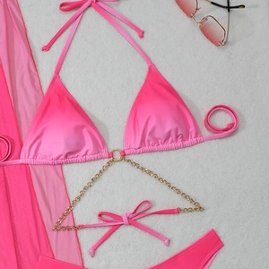 Detailed flat lay of gradient pink bikini set with mesh sarong and metal chain accents
