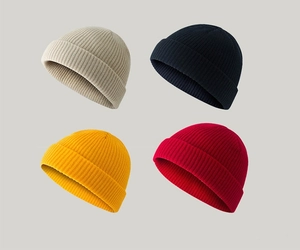 Flat lay of knit beanie hats in beige, black, yellow, and red showing soft texture