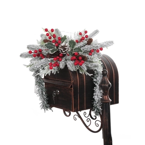 Close-up of frosted Christmas wreath with red berries and pinecones on a metal mailbox