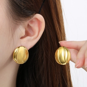 Detailed view of golden oval earrings with minimalist embossed streamline textures