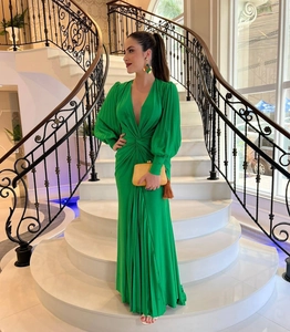 Detail of elegant emerald green pleated satin evening dress with deep V-neck and long sleeves