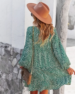 Rear view of a green polka dot long sleeve maxi dress styled with a brown wide-brimmed hat