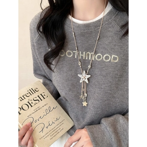 Detail of star pendant necklace with fringe on leather cord worn with casual sweater