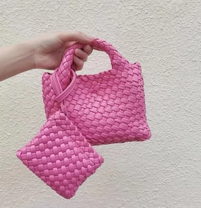 Detailed view of a pink woven bucket bag with a matching mini charm hanging on handle
