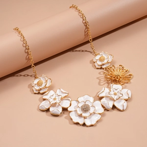 Macro shot of gold floral necklace with white enamel petals and sparkling rhinestones