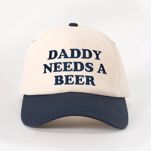 Close-up of DADDY NEEDS A BEER navy blue embroidery on a cream cotton baseball cap