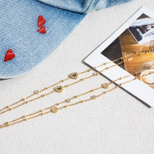 Detail of gold layered bead chain bracelet with heart and round crystal charms