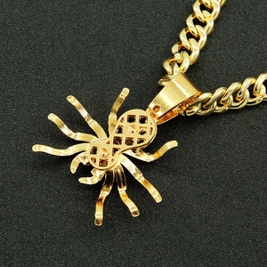 Detail shot of a gold-plated spider pendant with sparkling crystals on a chunky cuban chain