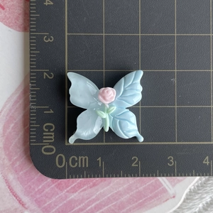 Macro view of macaron-colored resin butterfly with a pink rose for DIY crafts accessories