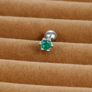 Detail shot of silver cartilage piercing with six-prong set green round cubic zirconia