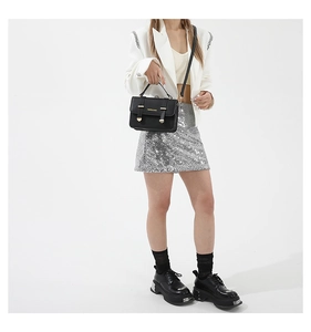 Detail shot of a black leather crossbody bag and platform loafers with silver accents