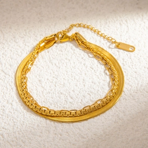 Detailed close-up of 18k gold plated layered herringbone and link chains on white texture