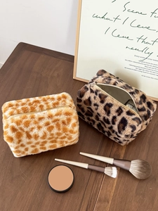 Detail of plush animal print makeup bags with durable zippers on a wooden surface