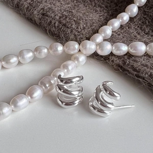 Macro shot of triple-layered sterling silver spiral stud earrings on a knit fabric base