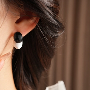 Close-up of black and white round stud earring on model with high gloss finish