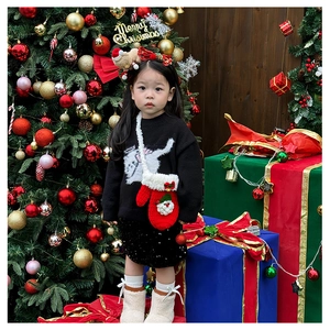 Détail d'une tenue de Noël pour enfant avec un sac à bandoulière en forme de gant tricoté