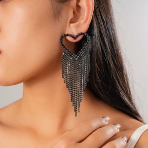 Close-up of black heart earrings with long sparkling rhinestone tassels on model