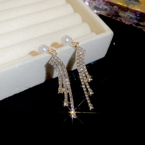 Detail of golden fringe earrings with elegant pearls and sparkling rhinestones on tray